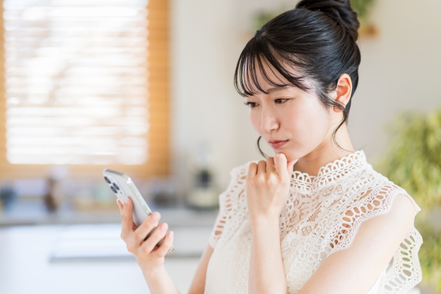 スマホを見ながら考える女性